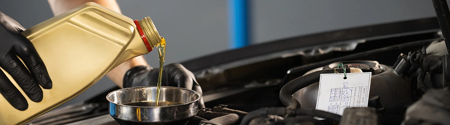 Mechanic adding oil to a car