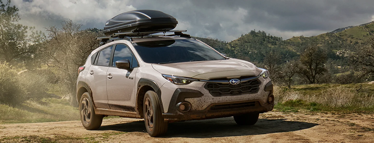 front view of a white 2026 Subaru Crosstrek Hybrid offroad with cargo carrier on top
