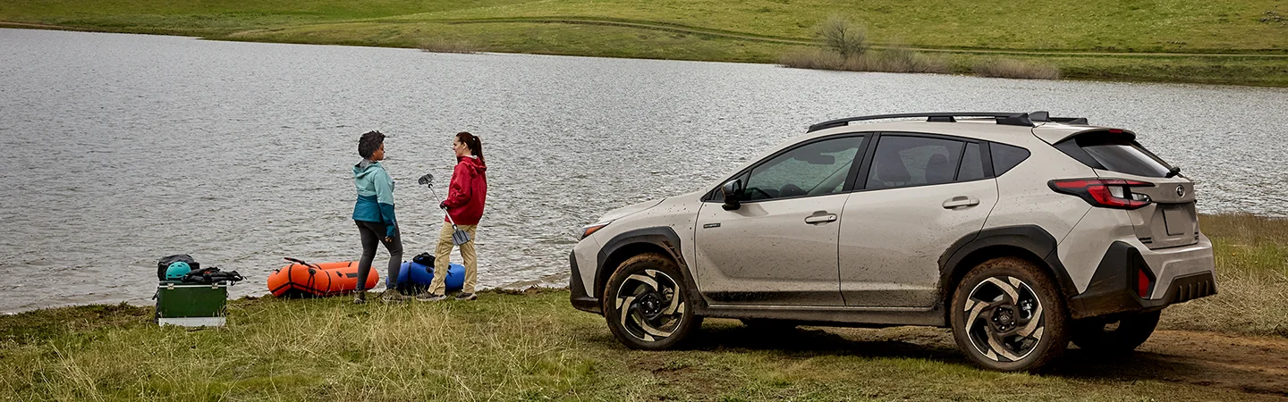 2026 Subaru Crosstrek Hybrid Sport by a lake with people sitting by lake
