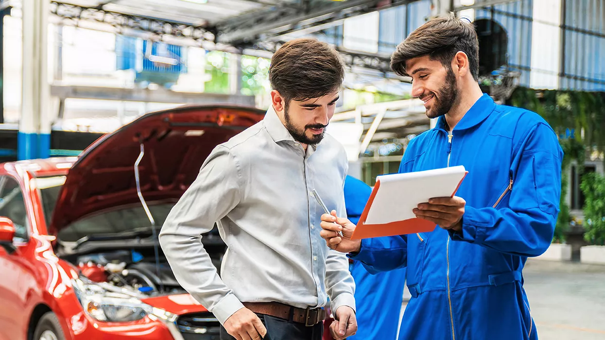 Mechanic holding a clipboard and talking to a customer