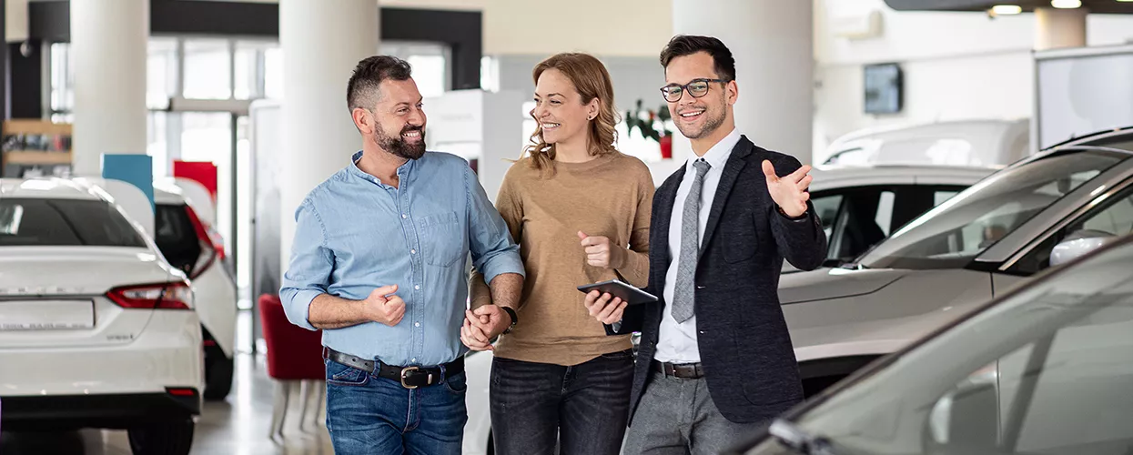 Car salesman showing a couple a new car in a dealership