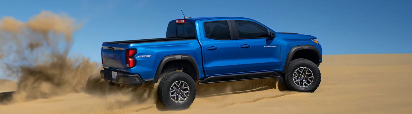 Blue 2024 Chevy Colorado raised truck driving in the sand