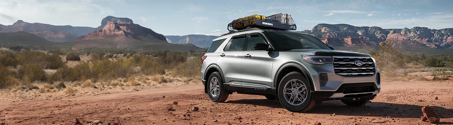 silver Ford Explorer in desert with gear strapped on rack on top