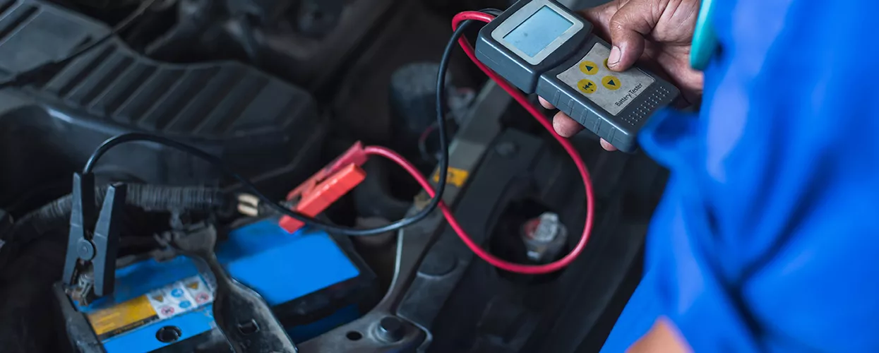 Service mechanic testing a car's battery