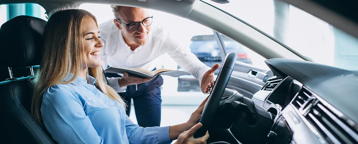 car salesperson showing another person a car's features