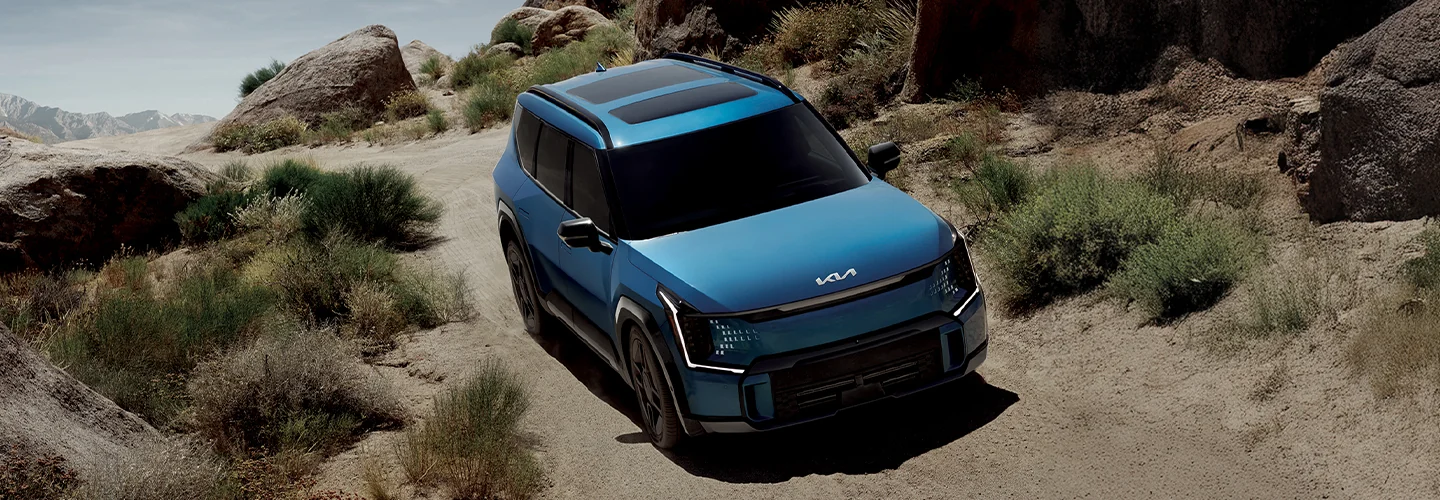 Blue 2025 Kia Electric driving in the wilderness