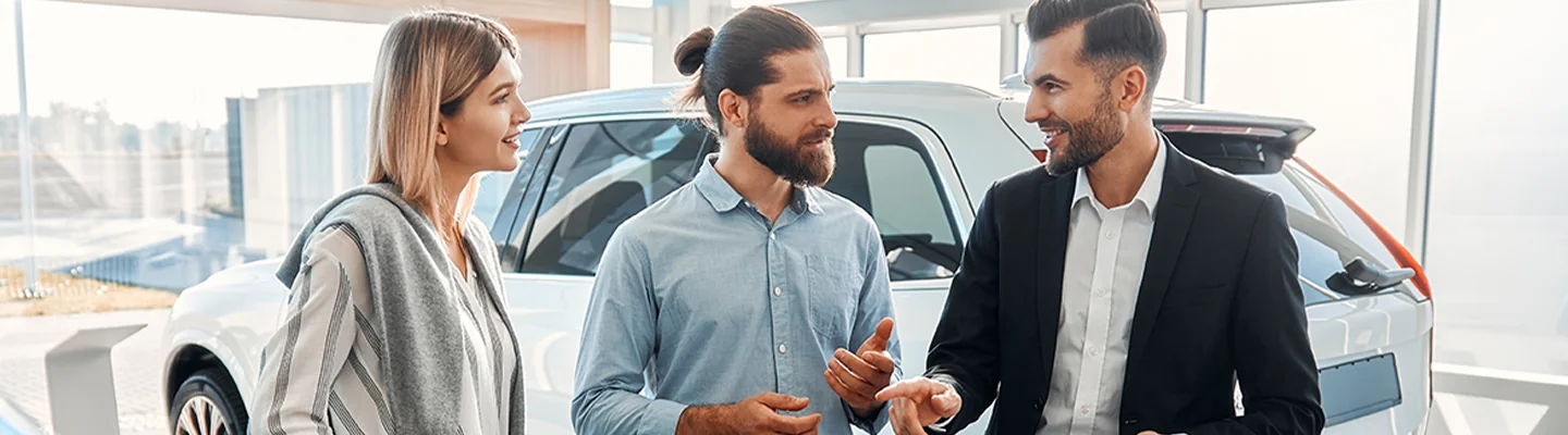 Sales person helping customers look at a new car