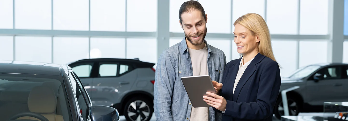 man and a woman go over specifications of a car lease in showroom
