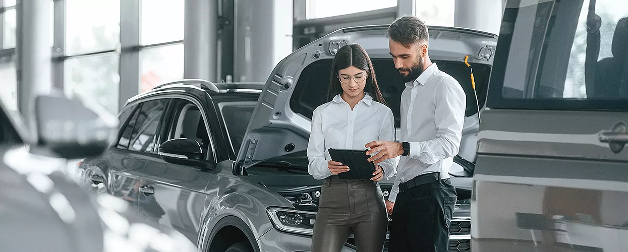 Two people standing in front of a car with the hood open