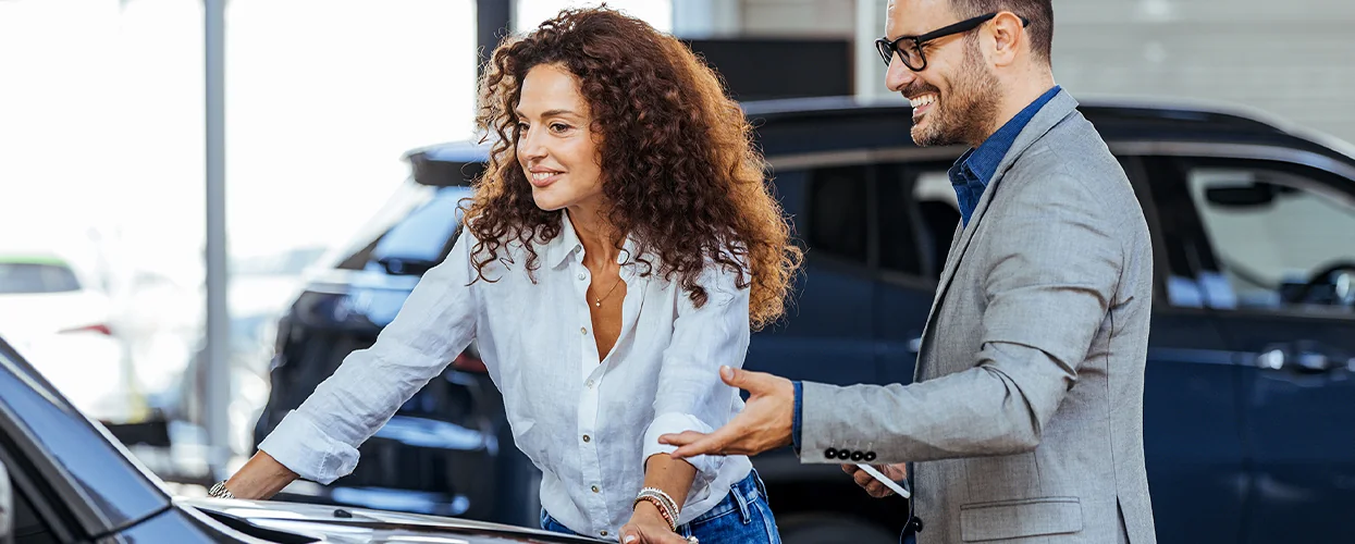 Sales person showing customer a new car
