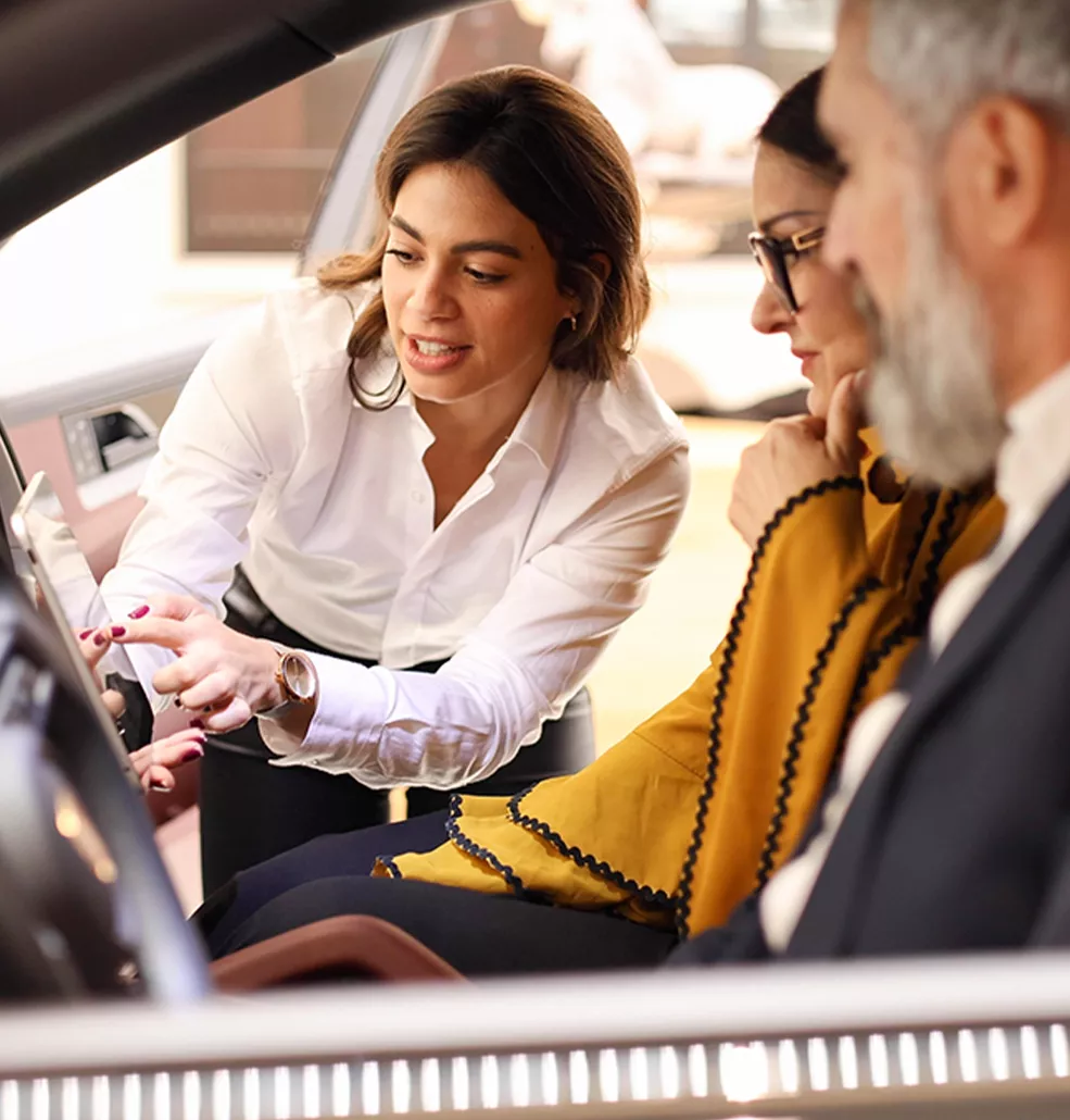 Sales person showing customers the inside of a car and its tech
