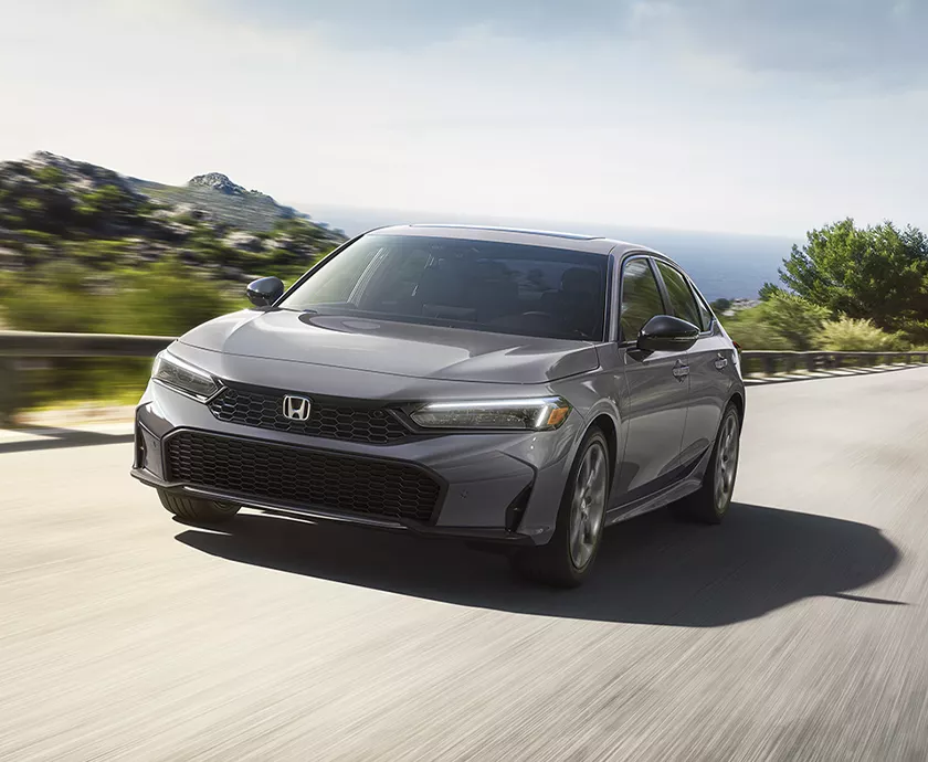 Front view of a gray 2027 Honda Civic driving next to the coast