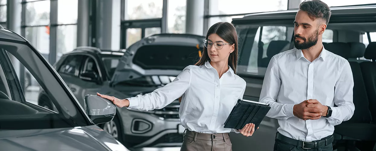 Car saleswoman showing a customer a new car