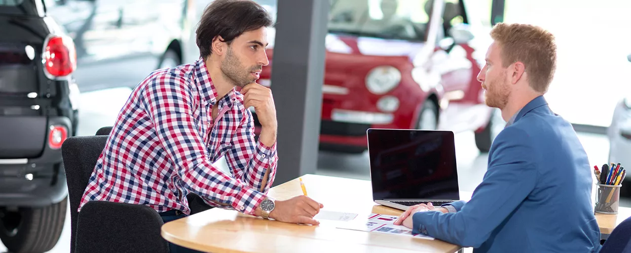 Customer and car salesman discussing a contract at a table