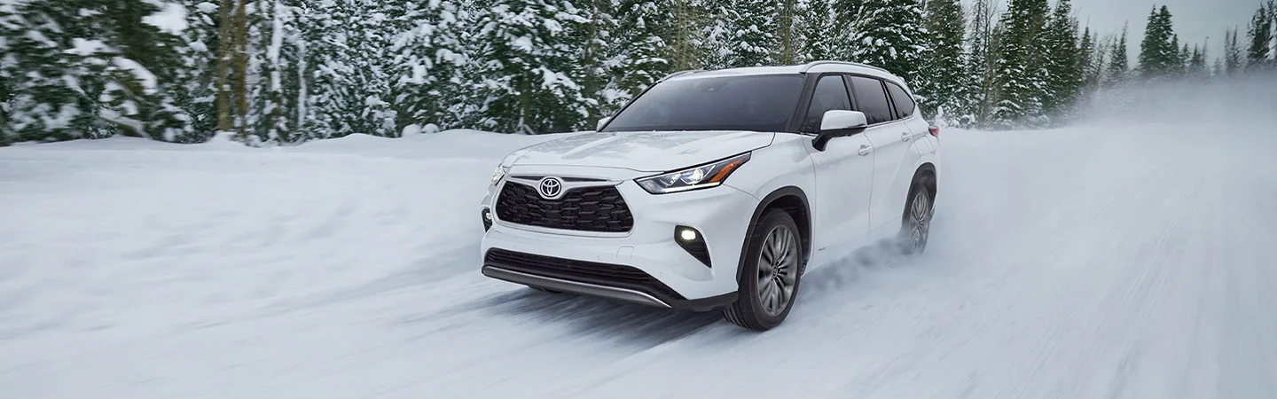 2025 Toyota Highlander driving down a country road in the snow