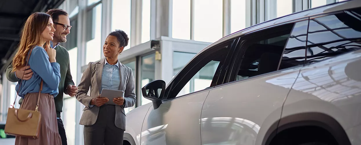 a couple at a car dealership discussing purchase with salesperson