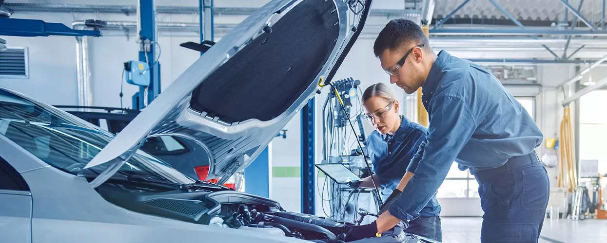 Service mechanics working on a car with the hood open