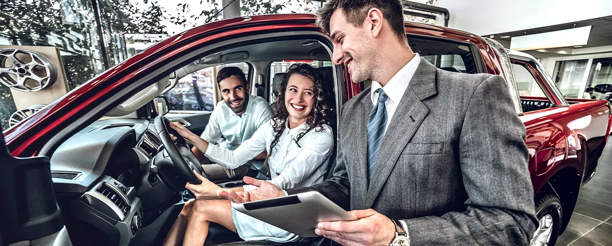 Couple sitting in a vehicle at a car dealership