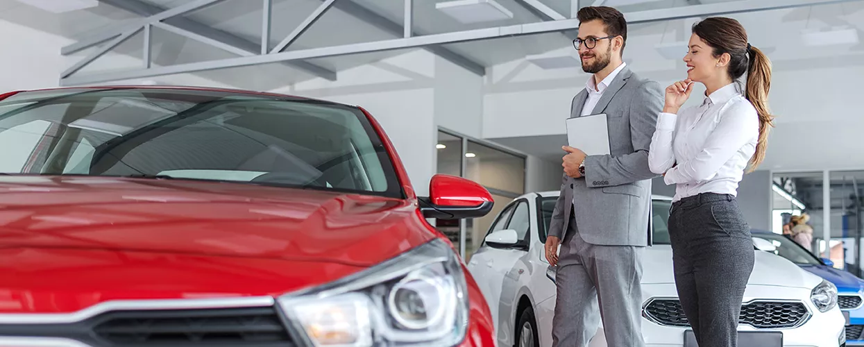 A sales person showing a customer new cars in the showroom