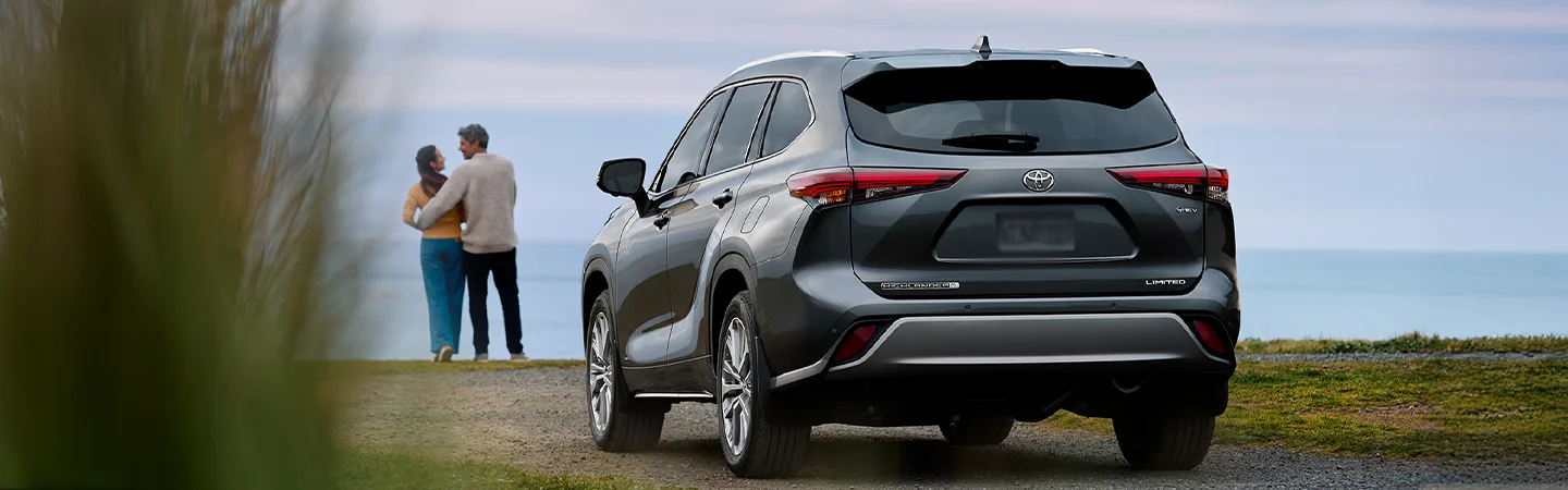 A couple embracing in front of a 2025 Toyota Highlander Hybrid