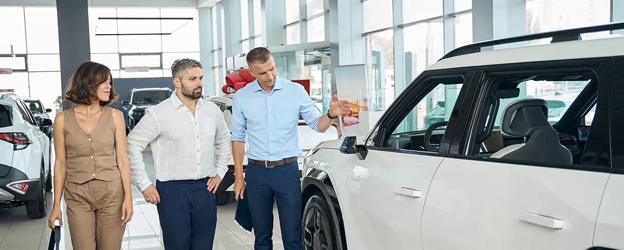 a car salesperson at a dealership showing a couple a new car