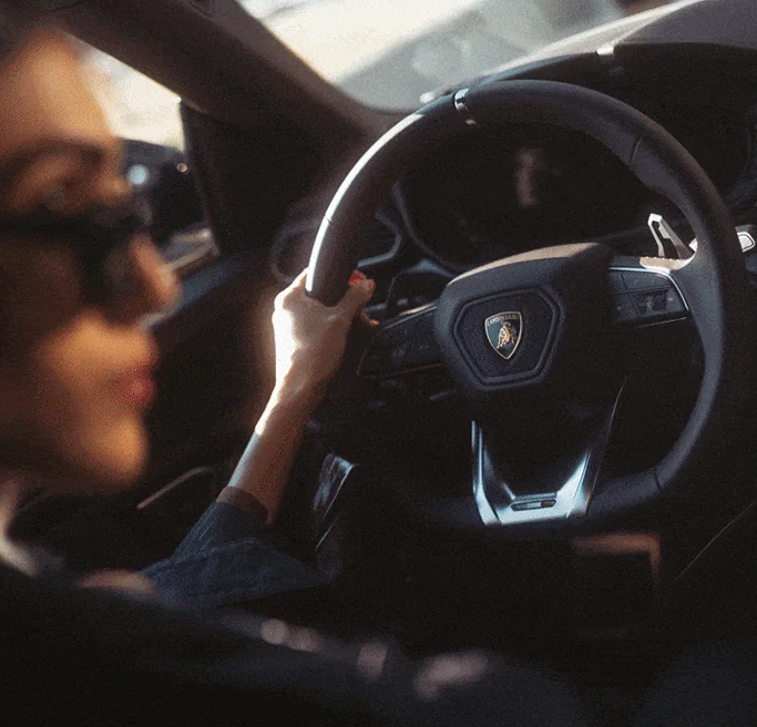 A woman behind the wheel of a car, navigating the road with concentration and confidence.