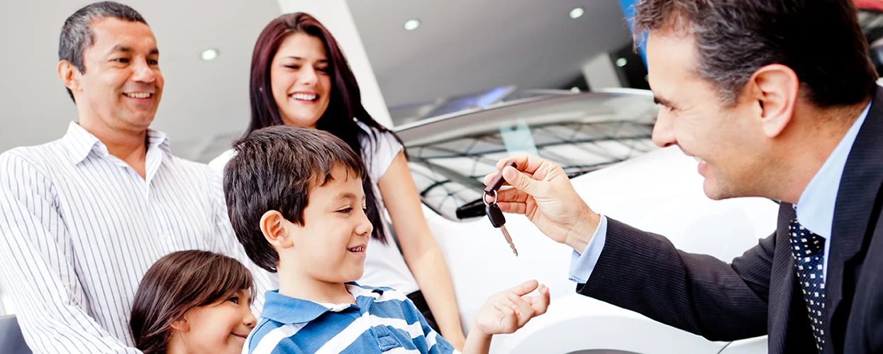 A man and woman hold a car key together, smiling as they prepare to unlock their vehicle.