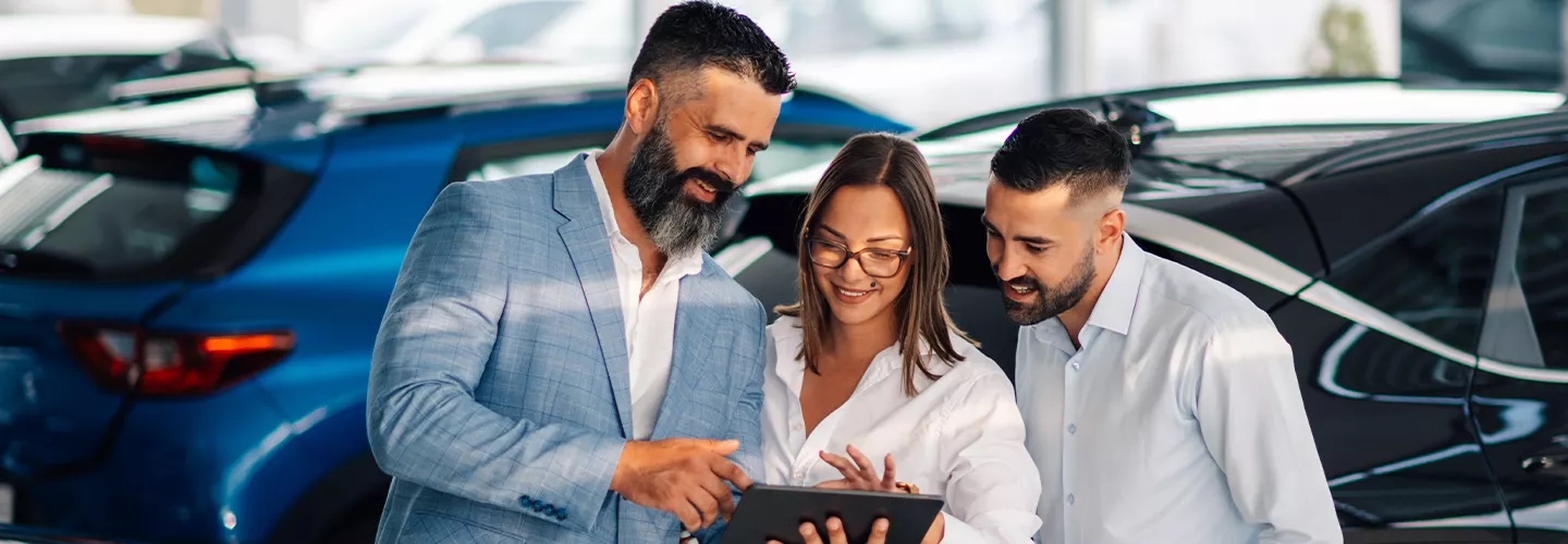 Car salesman talking to people at a car dealership