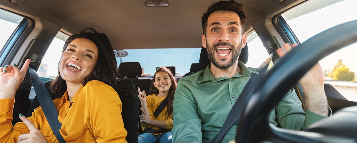 A happy family is driving in a car, all smiling and sharing a joyful moment during their journey.
