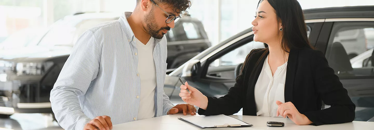 Car saleswoman going over a contract with a customer
