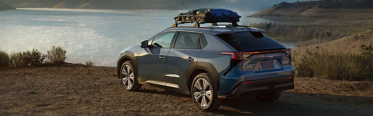 blue people in the desert next to blue Subaru Solterra near lake