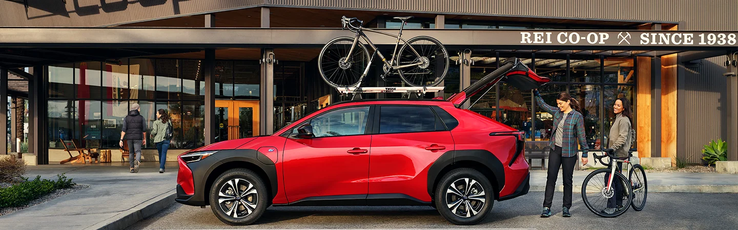 red profile image of people in the desert next to blue Subaru Solterra on street