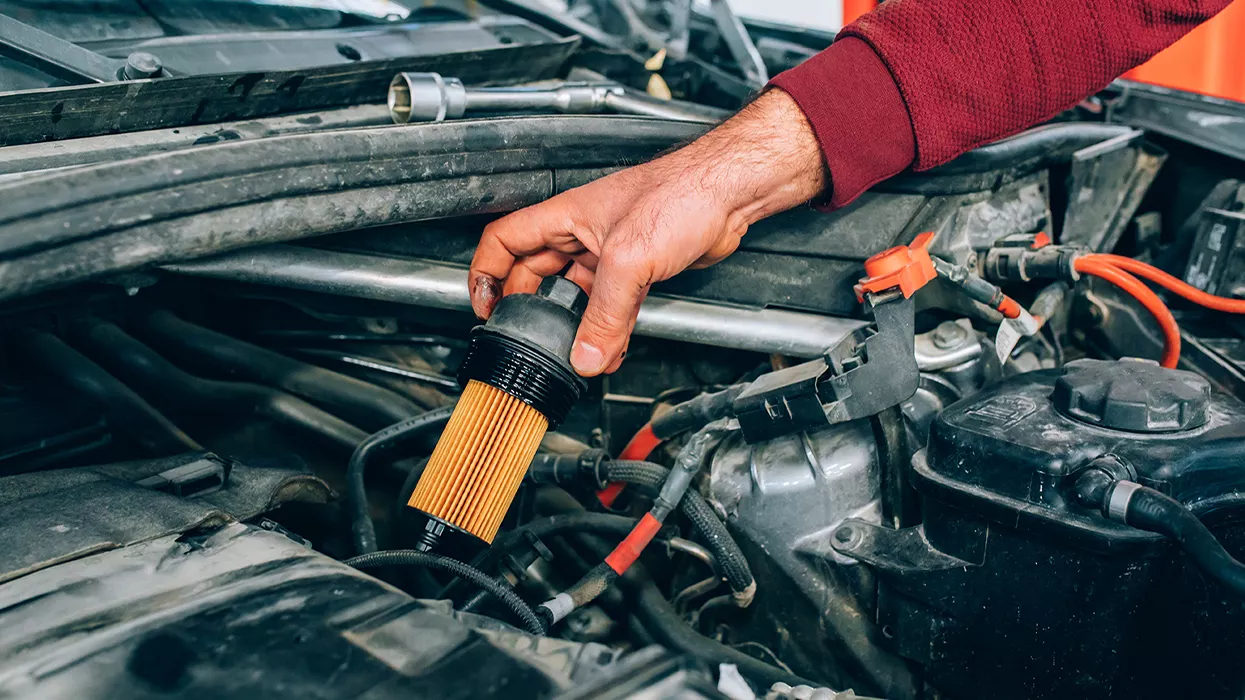 Service mechanic working on a car with the hood up