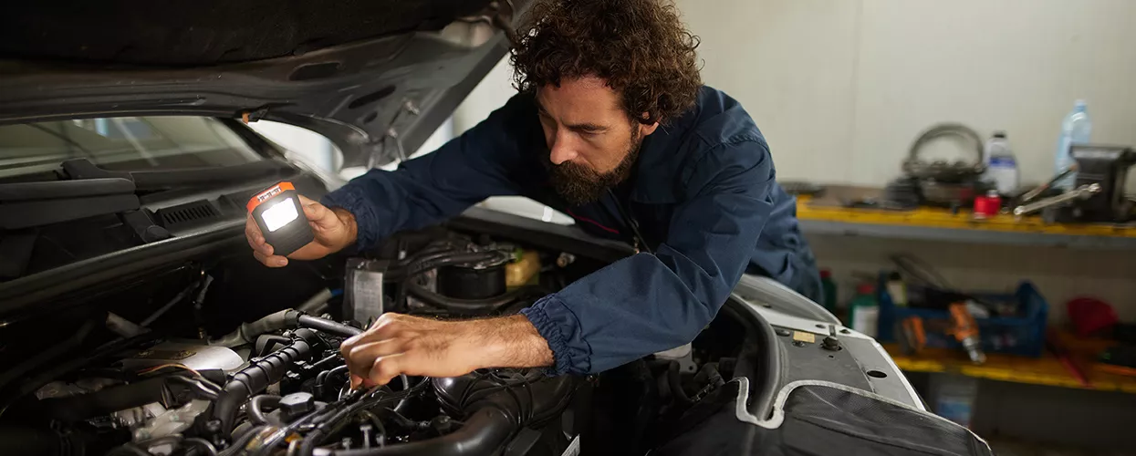 Service mechanic working under the hood of a vehicle