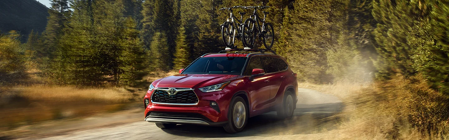 a red 2025 Toyota Highlander Hybrid XLE with two bikes racked on top