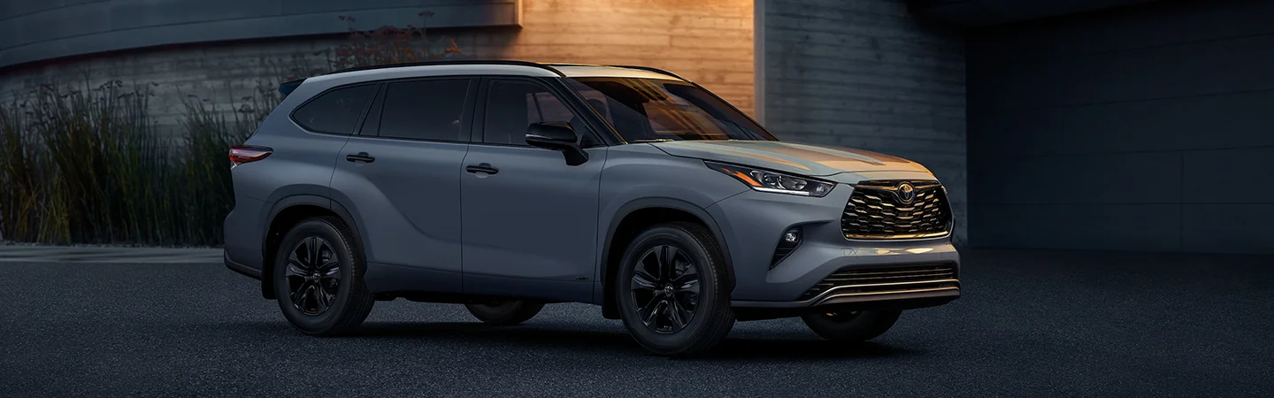 a gray 2025 Toyota Highlander Hybrid XLE parked by a home in the evening