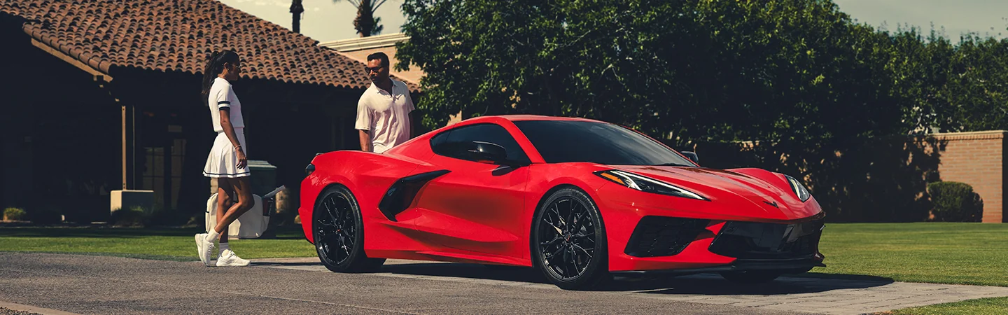 man and woman looking over Chevrolet Corvette