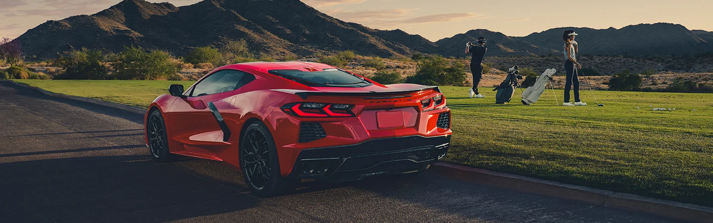Man and woman are playing golf after parking the Chevrolet Corvette on the highway