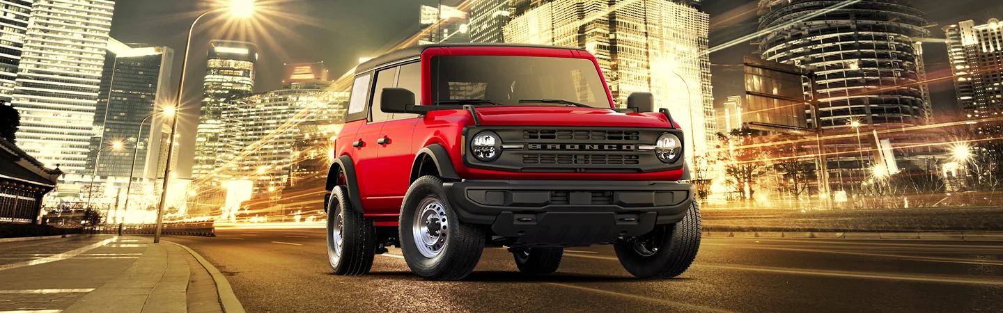 2025 Jeep Wrangler vs Ford Bronco Red color jeep on city road
