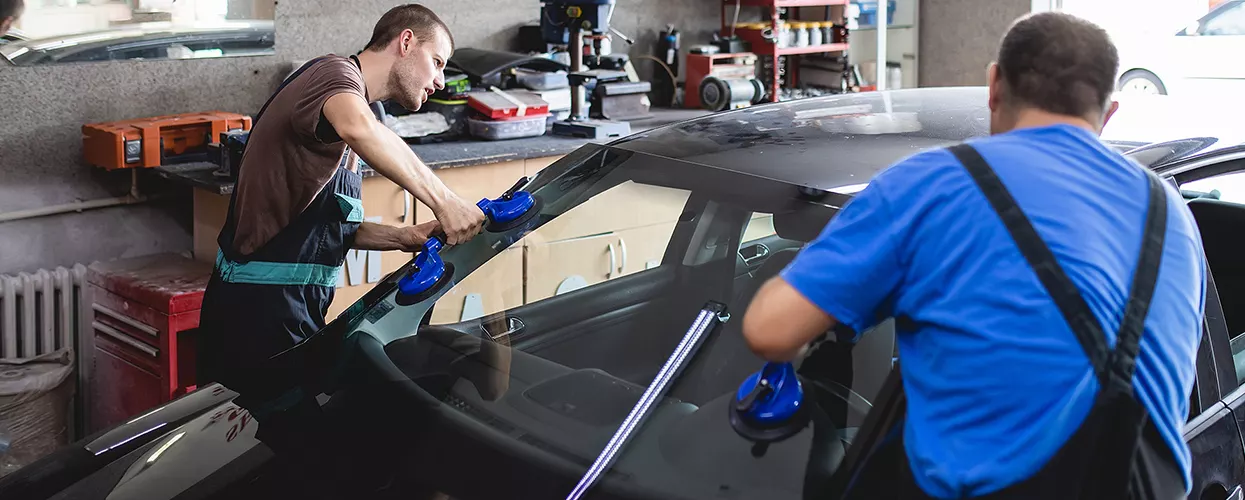 Service mechanics putting a new windshield on a vehicle