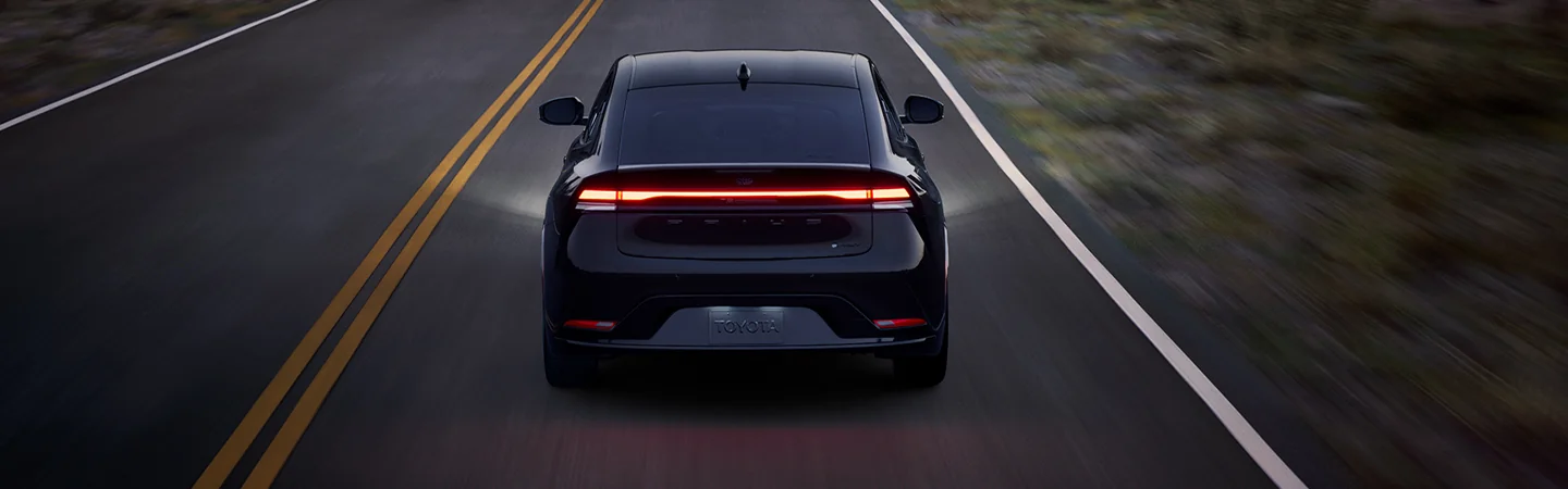 Back view of a black 2026 Toyota Prius driving on a raod at night