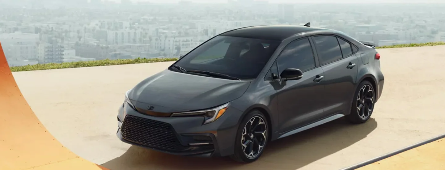A gray 2024 Toyota Corolla parked with the city in the background