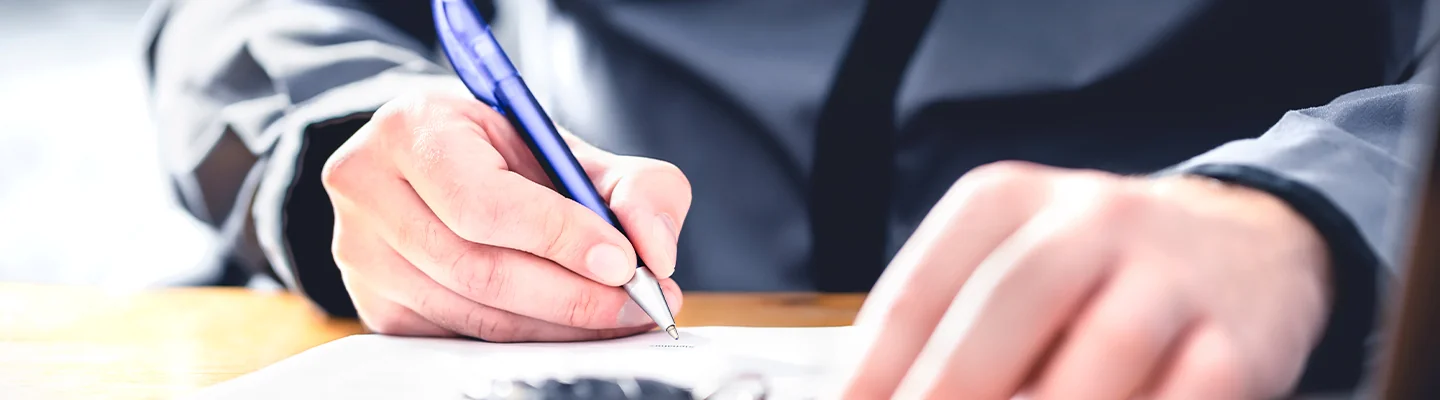a person about to write on pad just showing hands on table