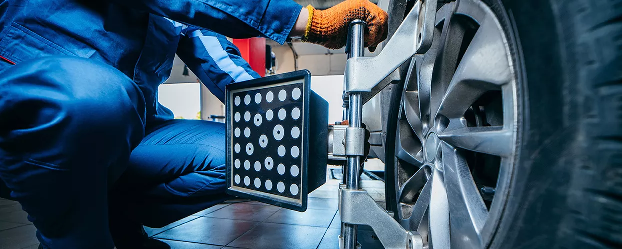 auto mechanic working on wheel alignment in service bay of dealership