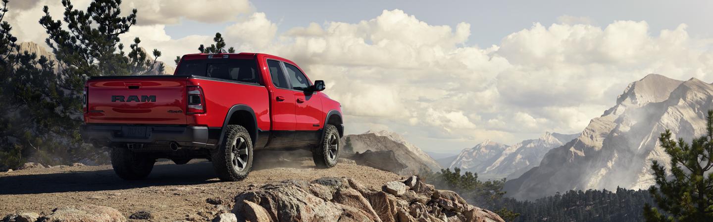 Rear view of a red 2021 RAM 1500 parked at a cliff overlooking the mountains.