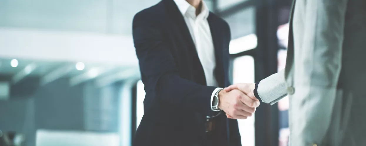 Two people shaking hands in a car dealership