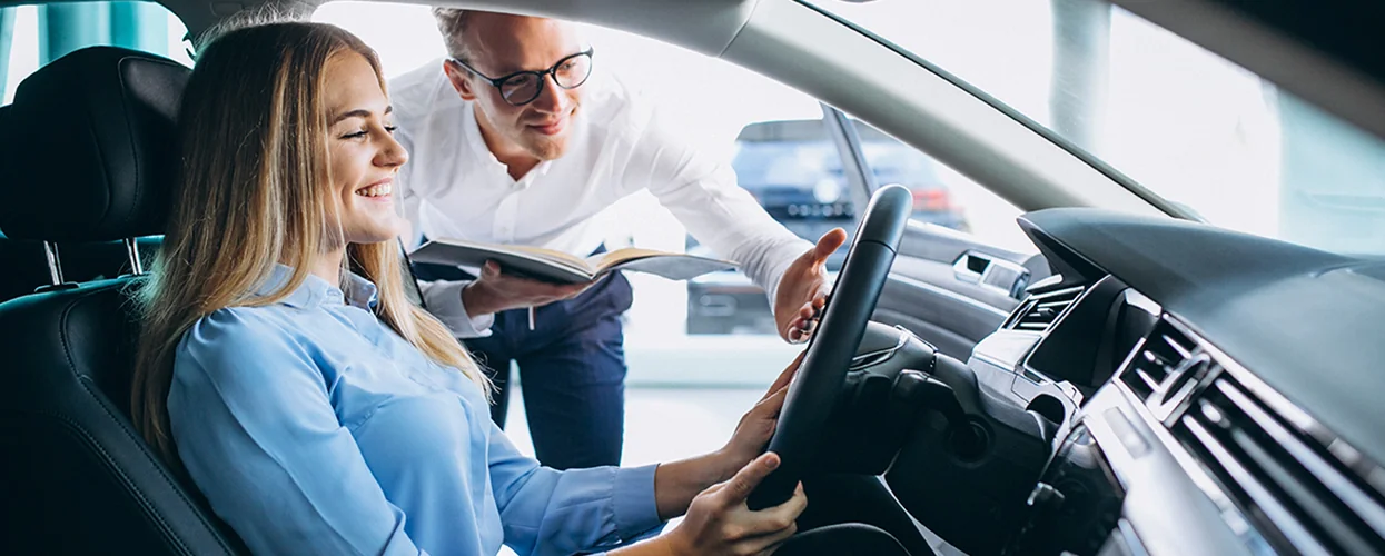 Sales person shwoing customer the inside of a new car