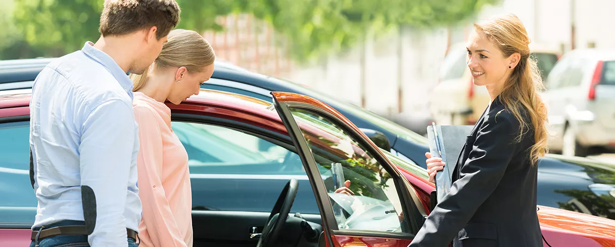 Car salesman showing a couple a new vehicle