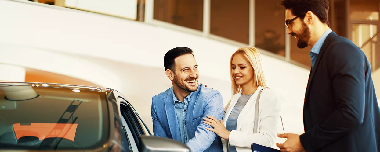 couple speaking with car salesperson in the dealership showroom