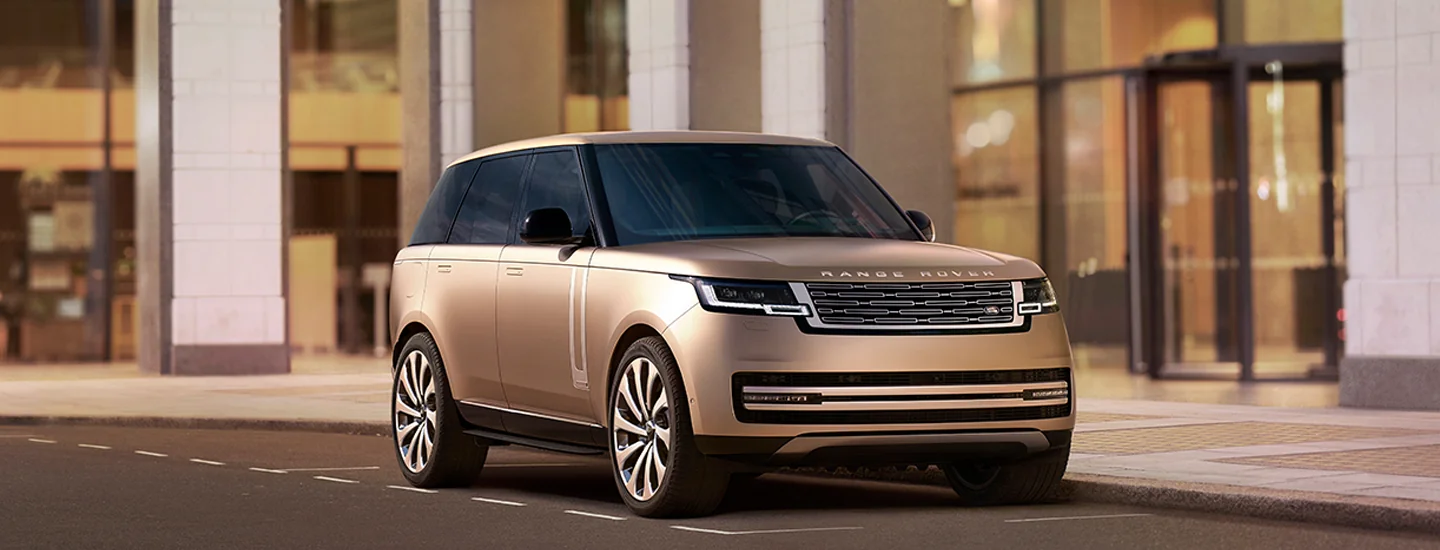 Copper 2025 Range Rover Hybrid parked in front of a building